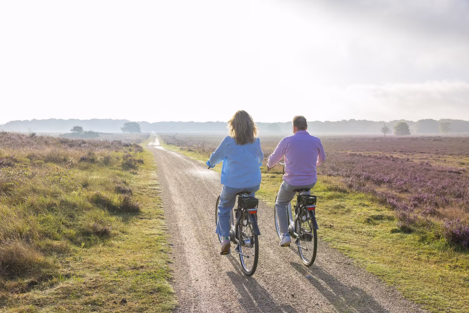 Twee mensen op e-bikes over een zandpad op de heide