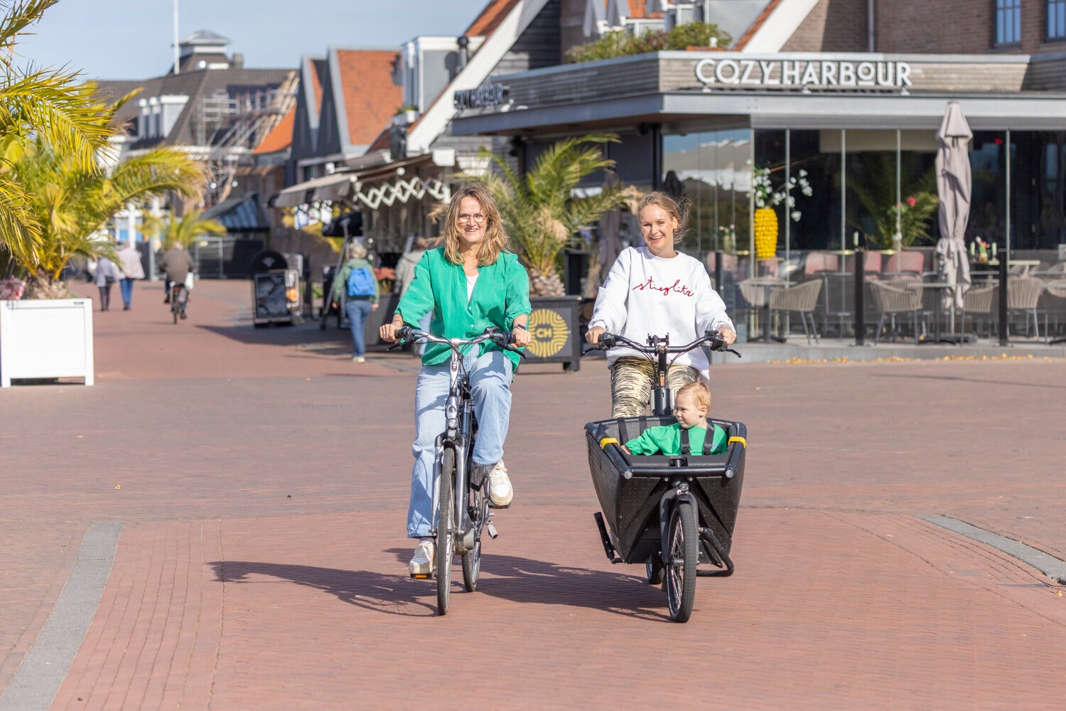 Moeder met kind op een bakfiets en vriendin op een elektrische fiets in Harderwijk