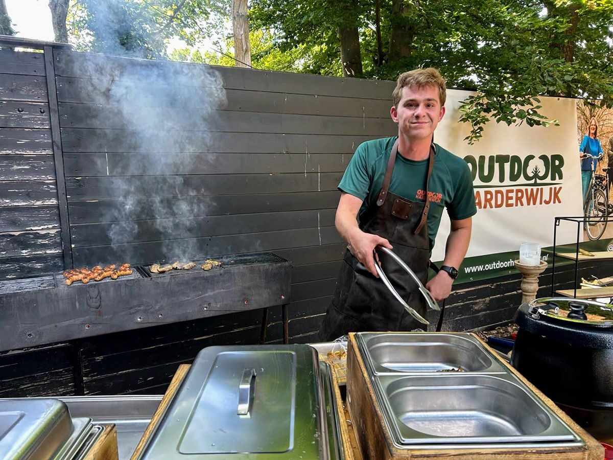 Medewerker achter de barbecue voor een bedrijfsuitje bij Outdoor Harderwijk