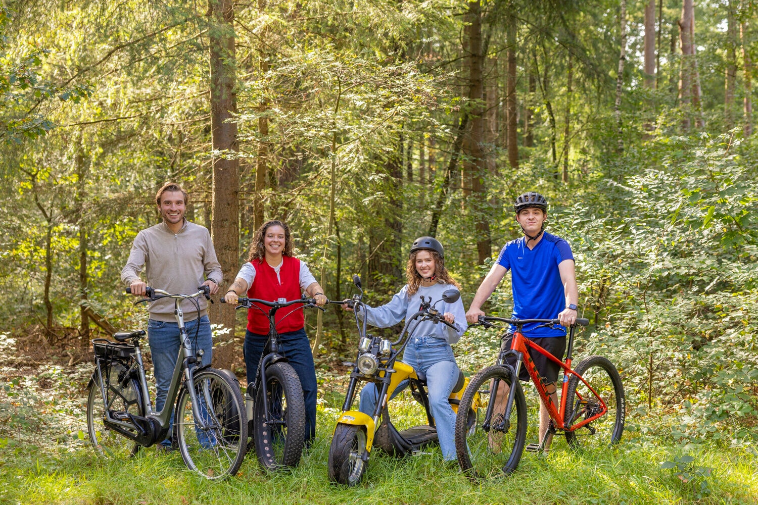 Vier vrienden met e-bike, e-step, e-chopper en mountainbike in het bos bij Outdoor Harderwijk