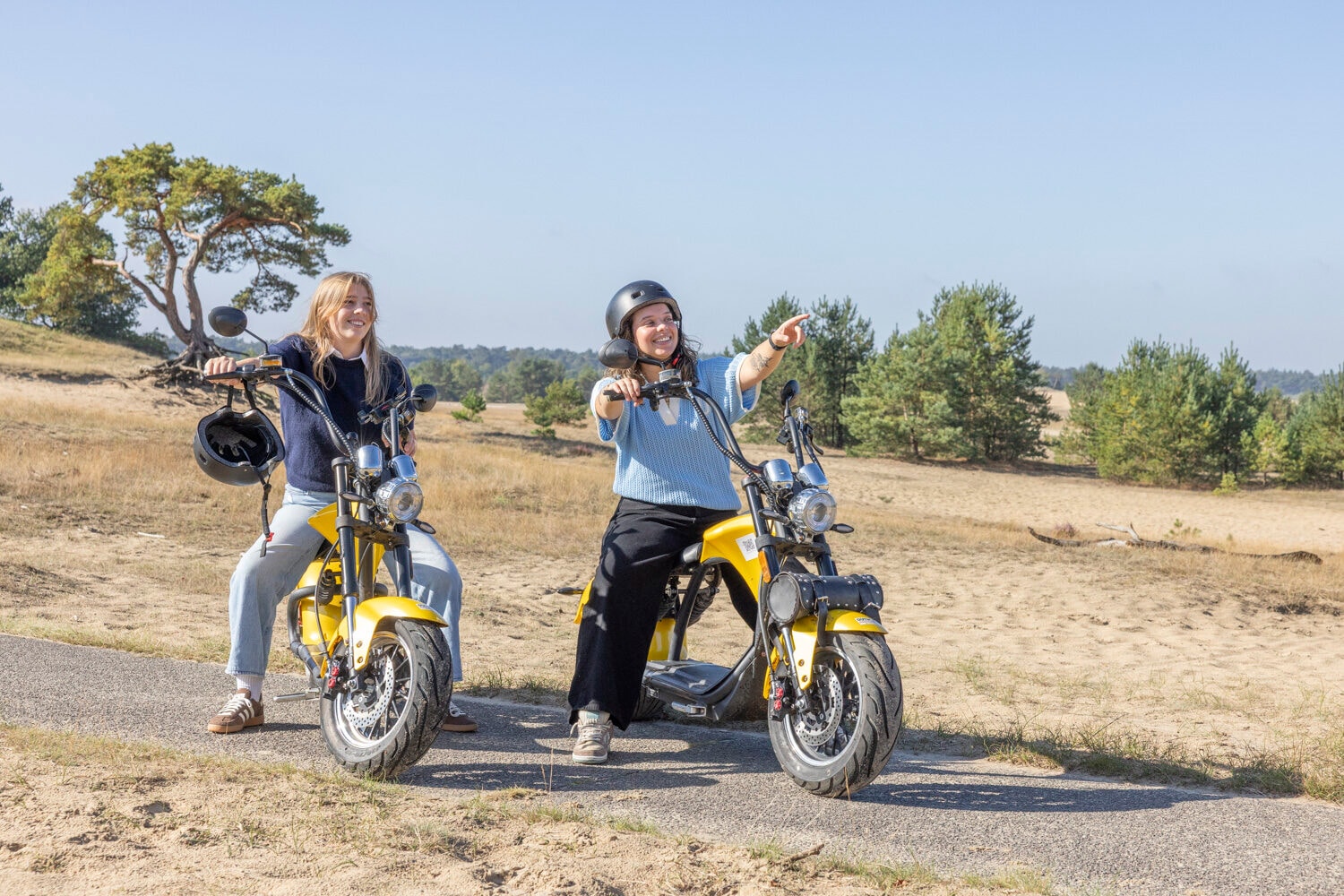 Zwei Frauen sitzen auf gelben E-Choppern im Sand bei Harderwijk