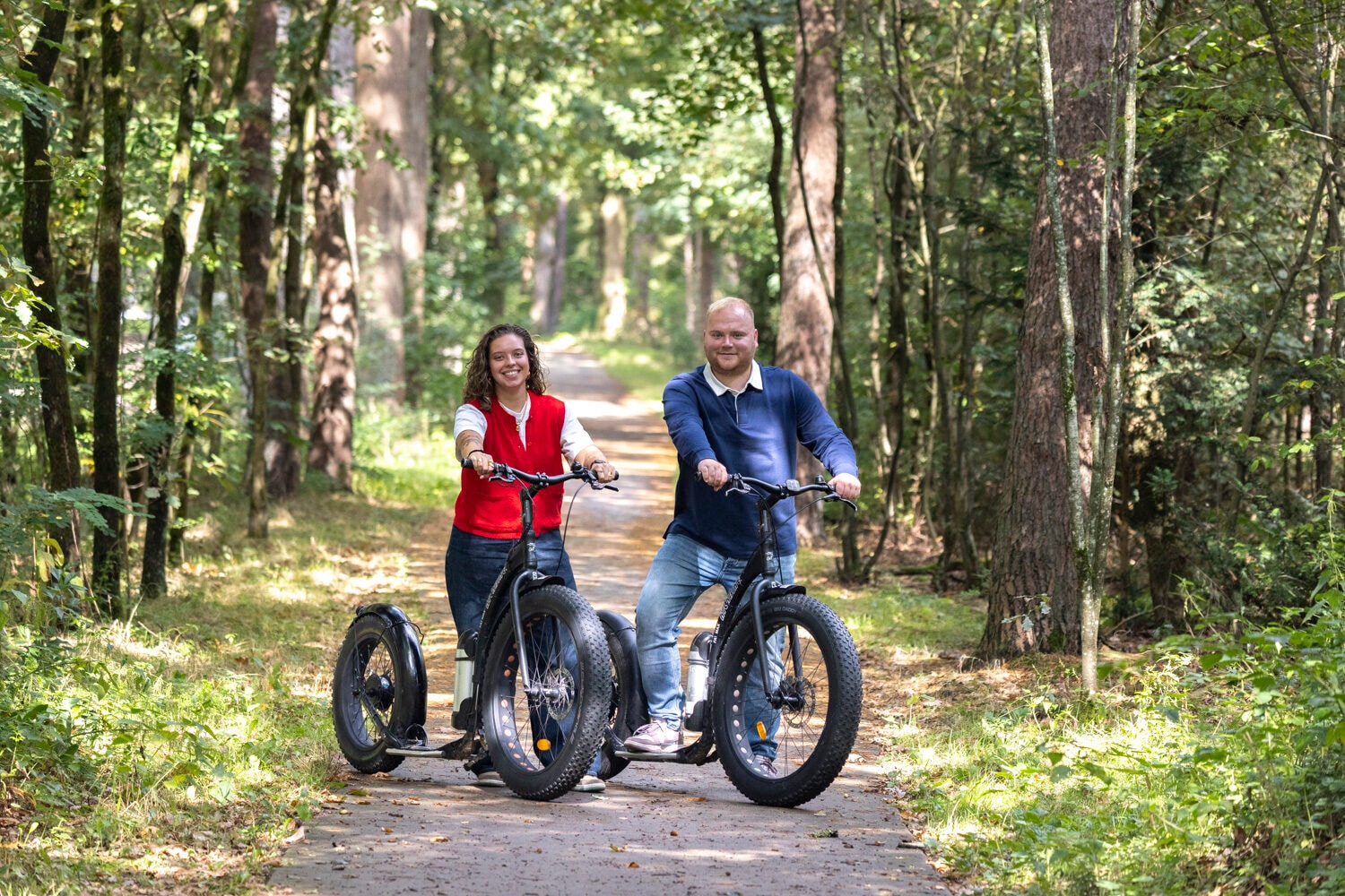 Frau und Mann auf E-Scootern im Wald bei Harderwijk