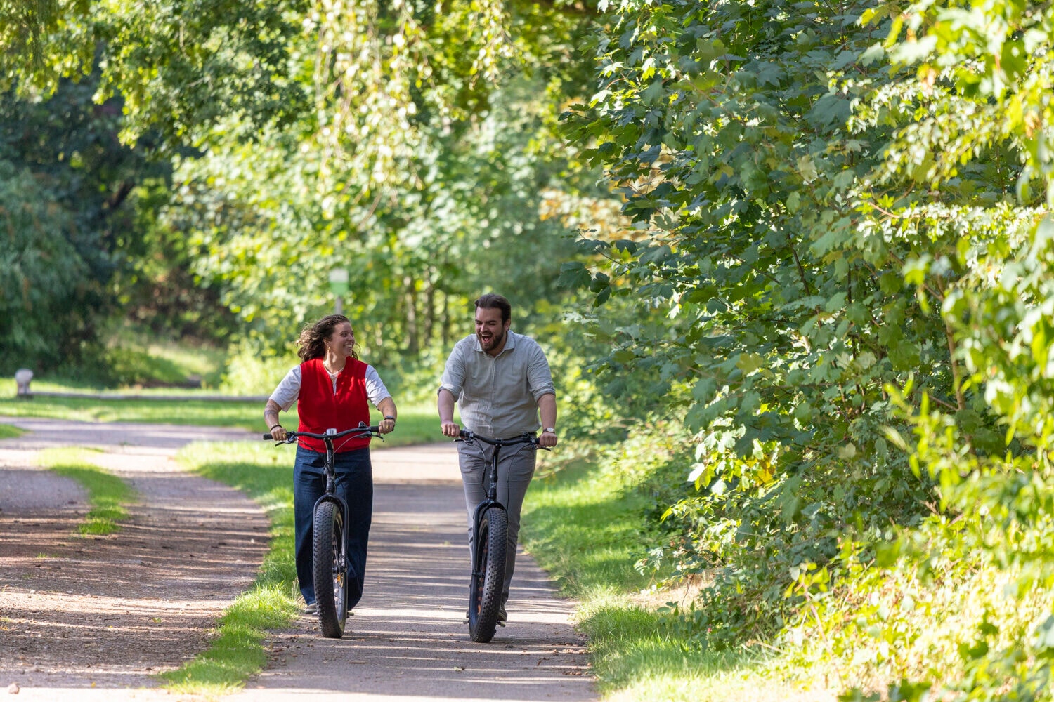 Mann und Frau mit E-Scootern auf einem Waldweg
