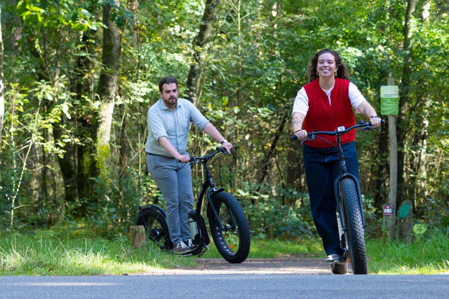 Mann und Frau auf E-Scootern auf einem Waldweg