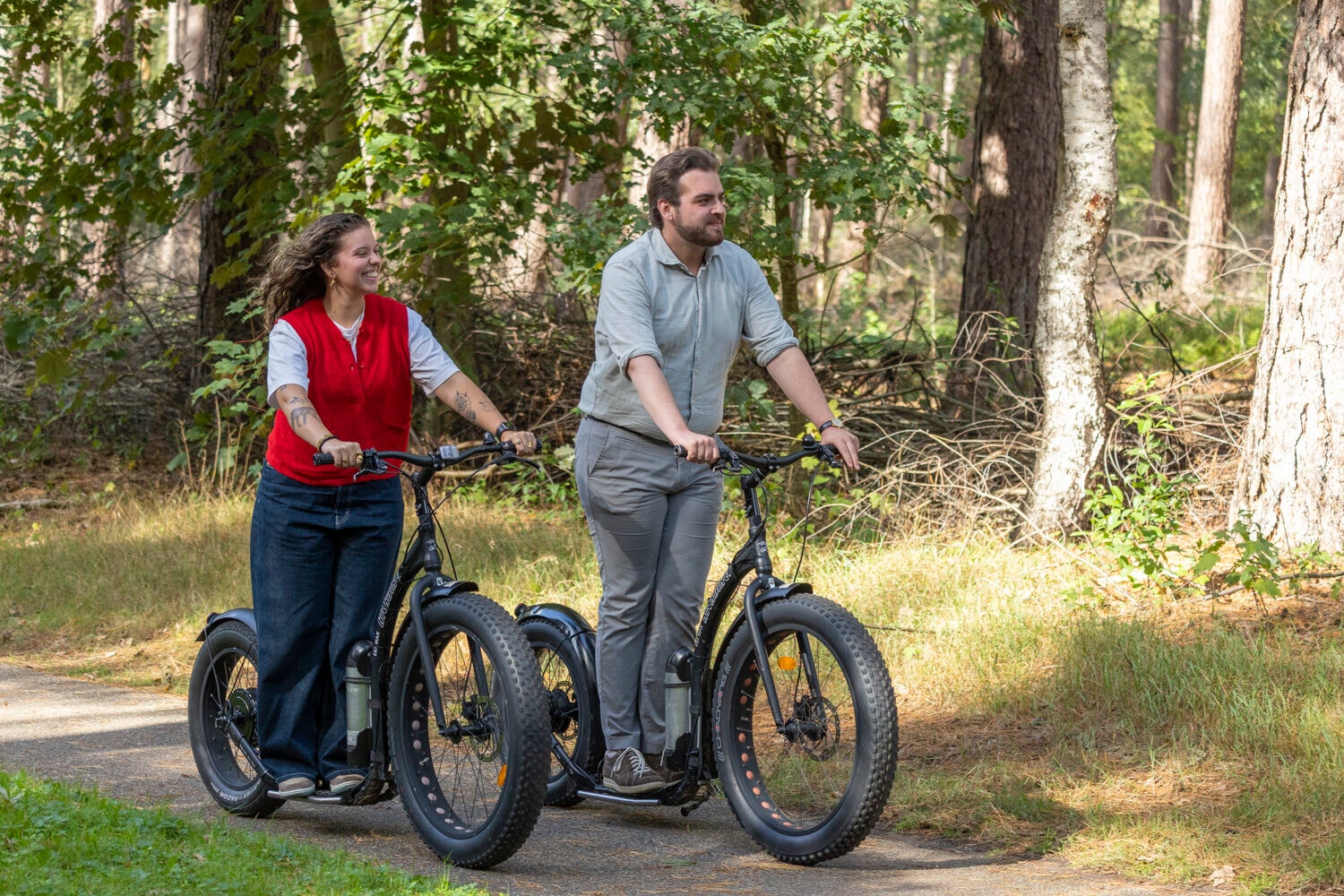 Mann und Frau auf E-Scootern im Wald