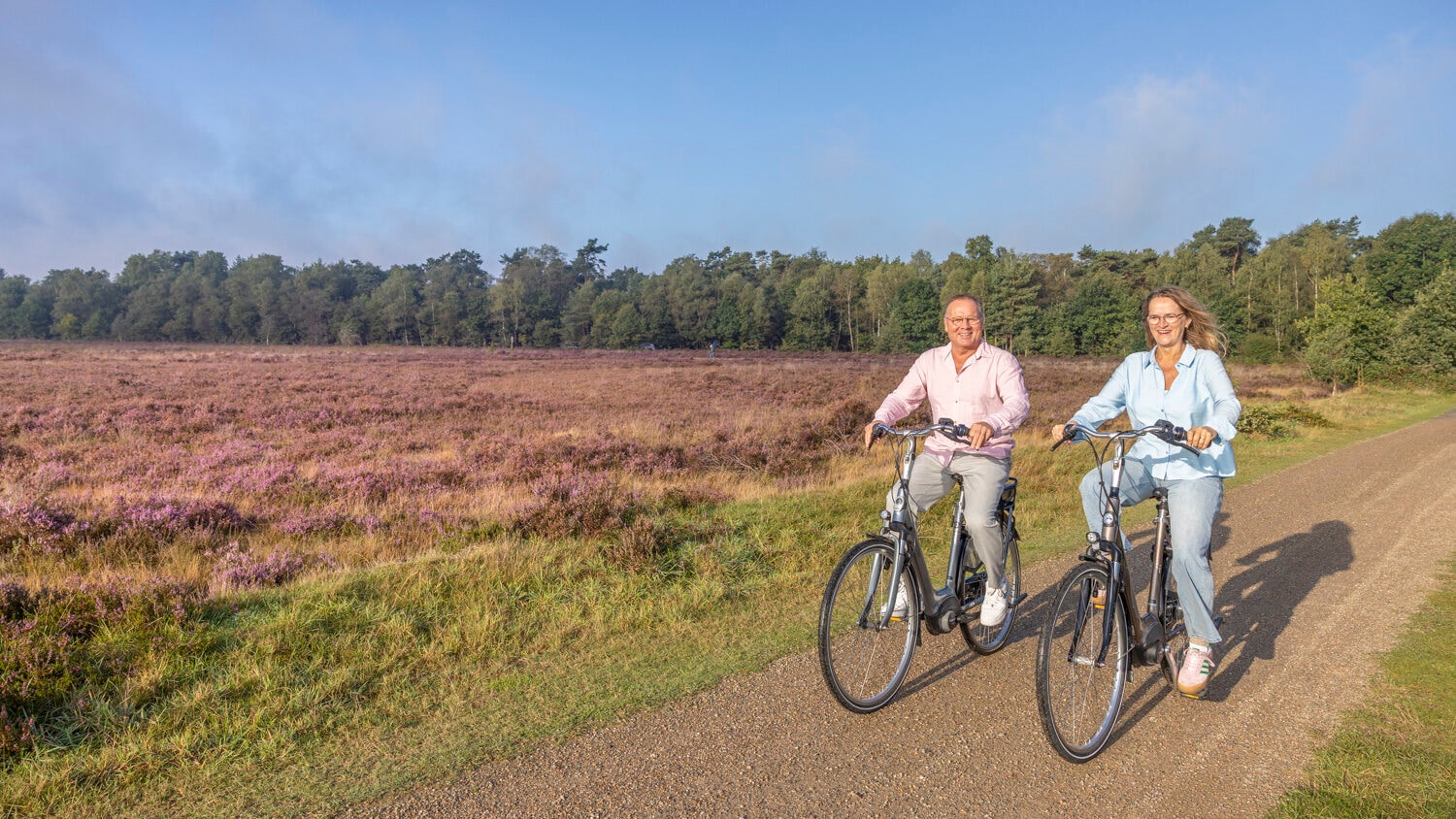 Zwei Erwachsene auf E-Bikes an blühender Heide in der Veluwe