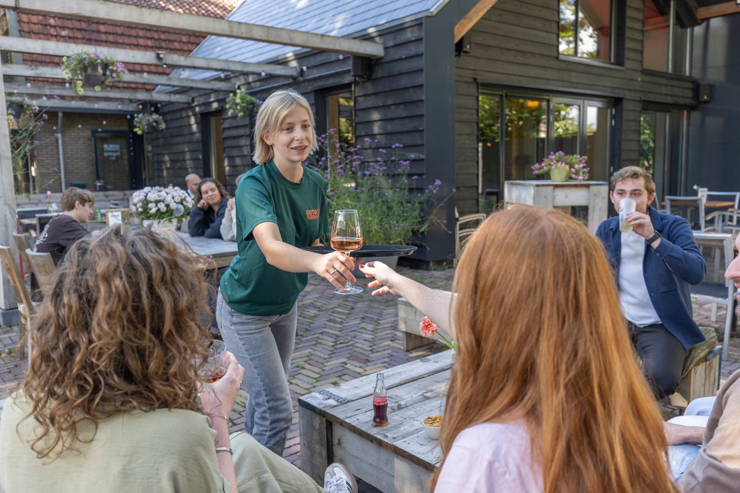 Medewerker serveert een drankje op het terras van Outdoor Harderwijk