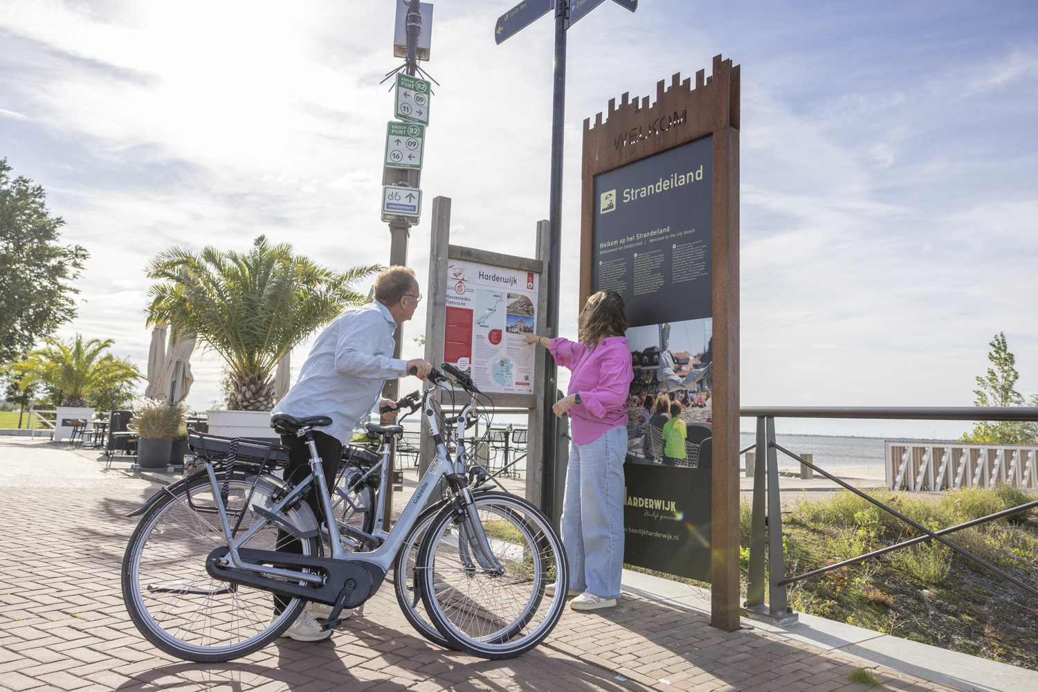 Stel op e-bike bekijkt routekaart bij knooppunt 82 op het Strandeiland Harderwijk