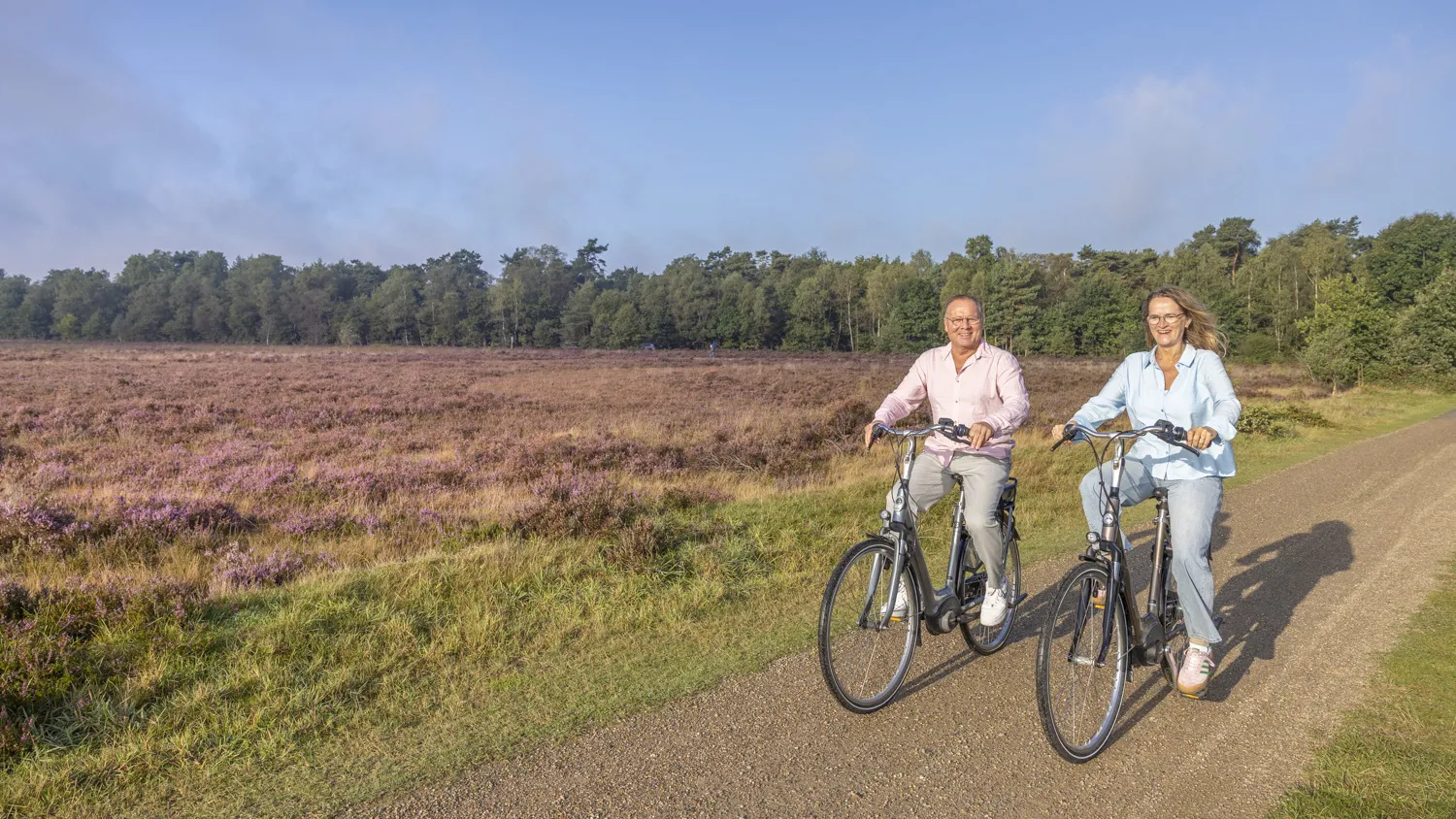 Stel fietst op e-bikes langs de bloeiende Ermelosche Heide
