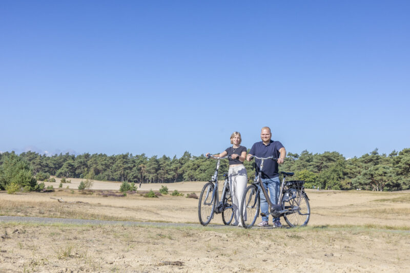 Twee fietsers met fietsen bij een zandverstuiving op de Veluwe tijdens een fietsroute bij Harderwijk