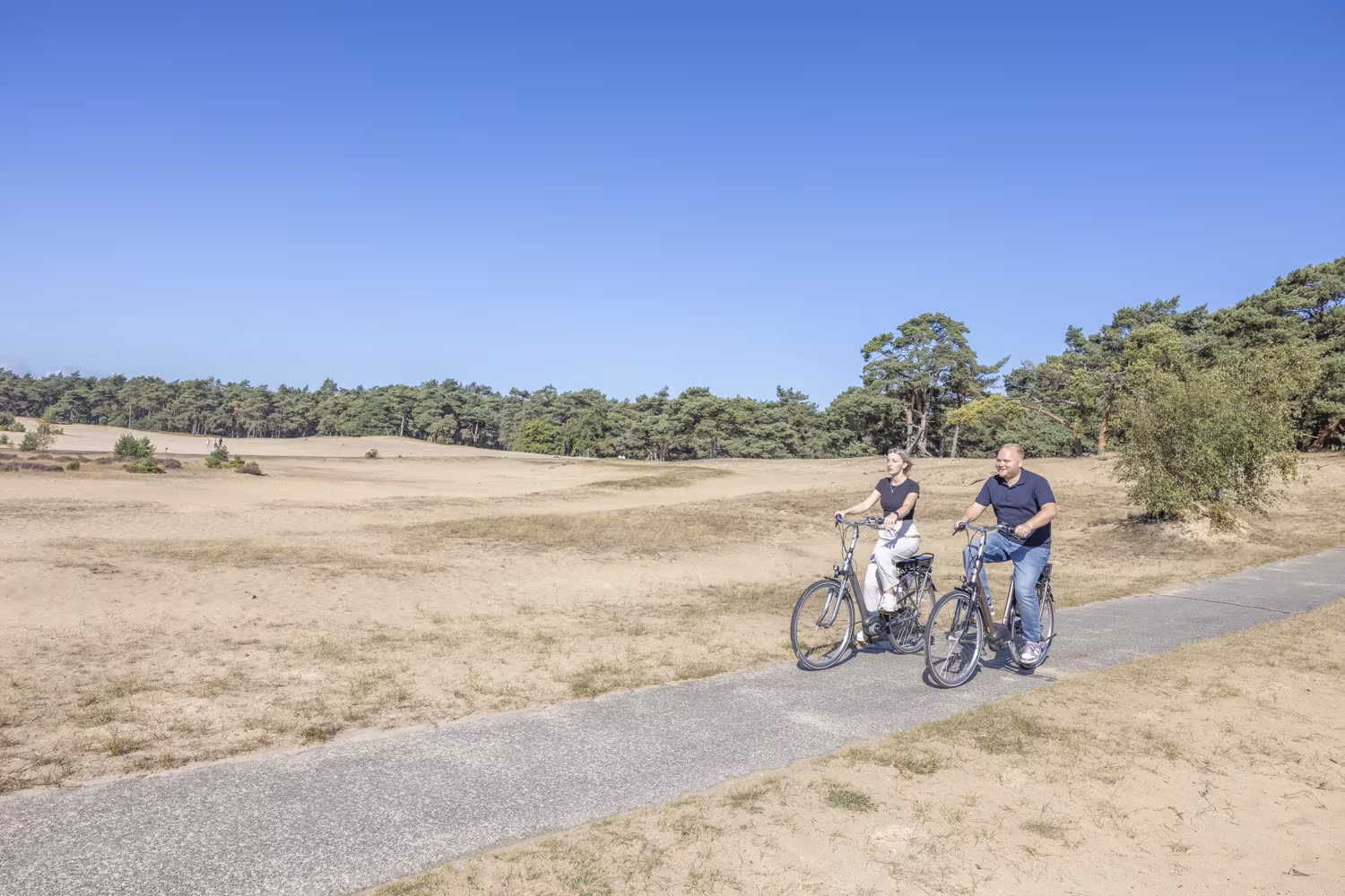 Stel fietst op e-bikes over het Beekhuizerzand op de Noord-Veluwe