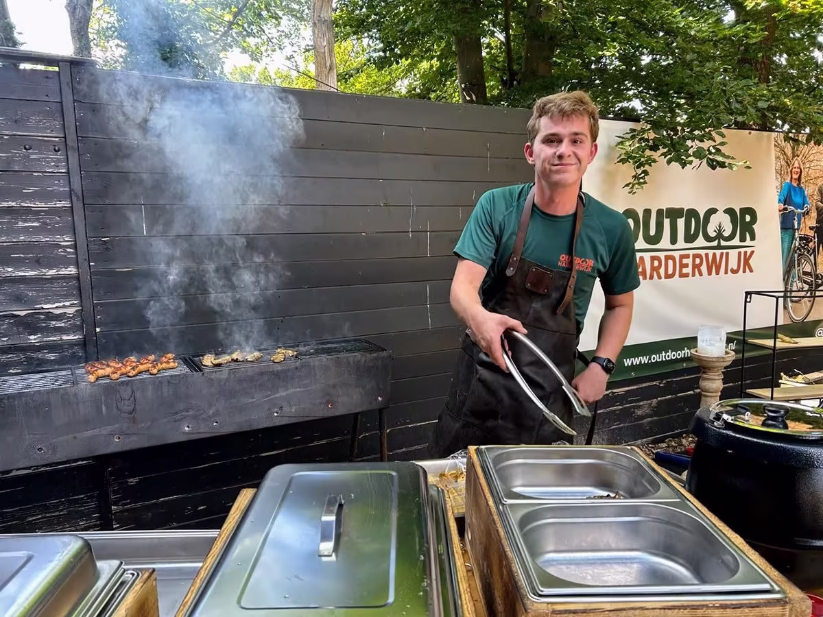 jongen achter BBQ voor bedrijfsuitje bij Outdoor Harderwijk